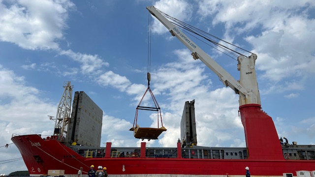 Shipboard crane lifting industrial cargo beside a project vessel